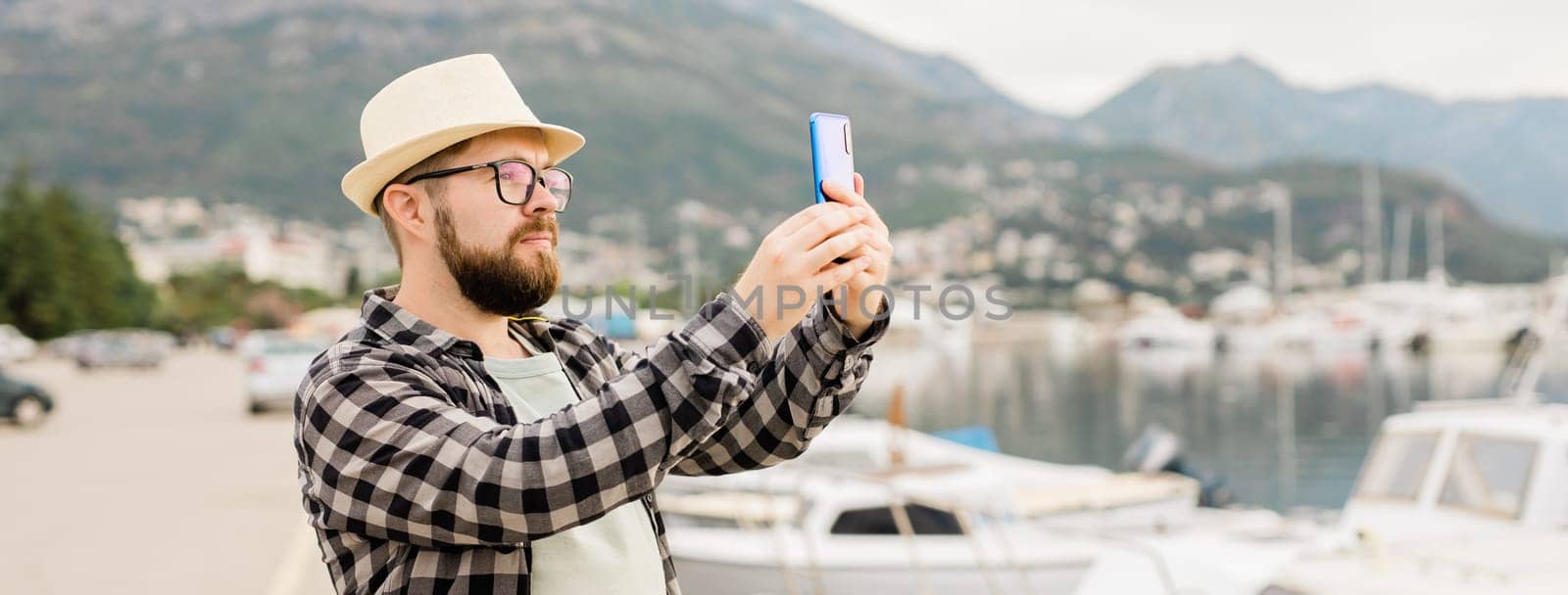 Traveller millennial man taking pictures of luxury yachts marine during sunny day - travel and summer banner with copy space by Satura86