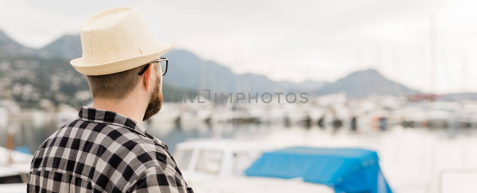 Rear view man wearing hat with yachts marina background with copy space and empty place for advertising