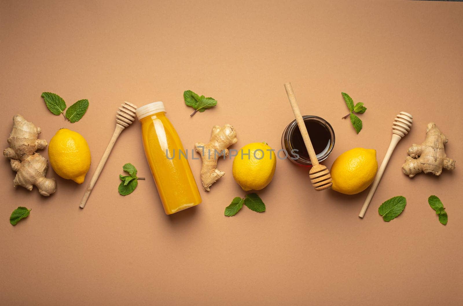 Composition with detox drink, lemons, mint, ginger, honey in glass jar, honey wooden dippers top view. Food for immunity stimulation and against flu. Healthy natural remedies to boost immune system.
