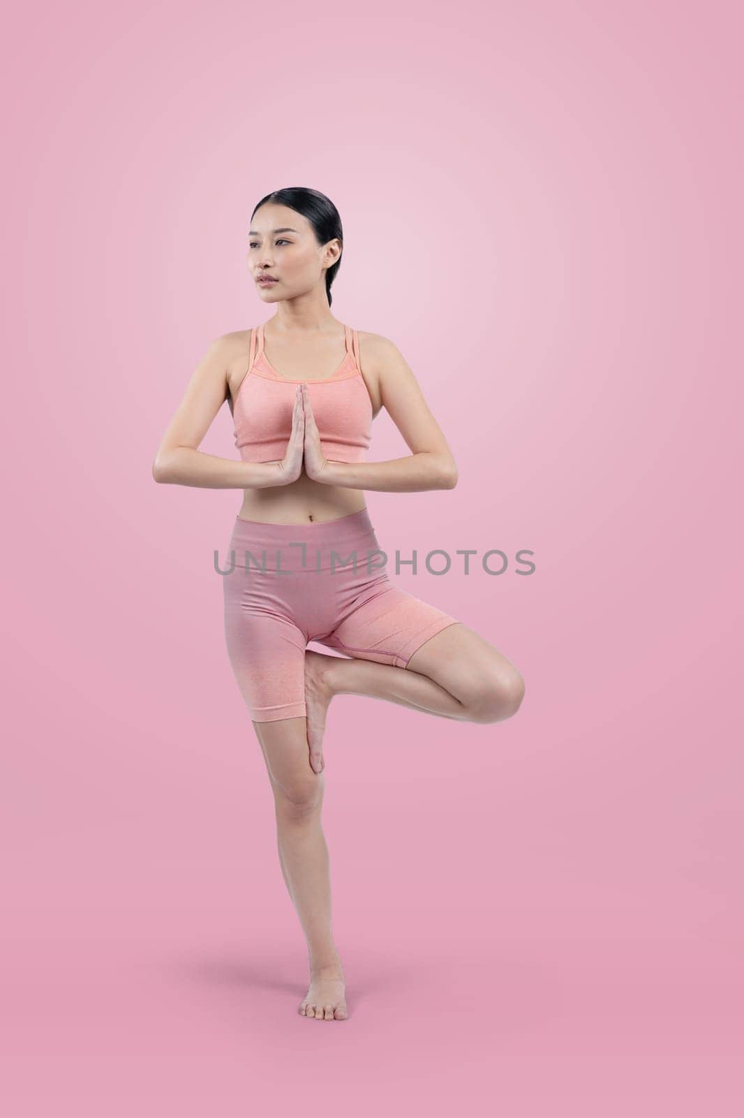 Asian woman in sportswear doing yoga exercise in standing pose on fitness as her workout training routine. Healthy body care and meditation yoga lifestyle in full shot on isolated background. Vigorous