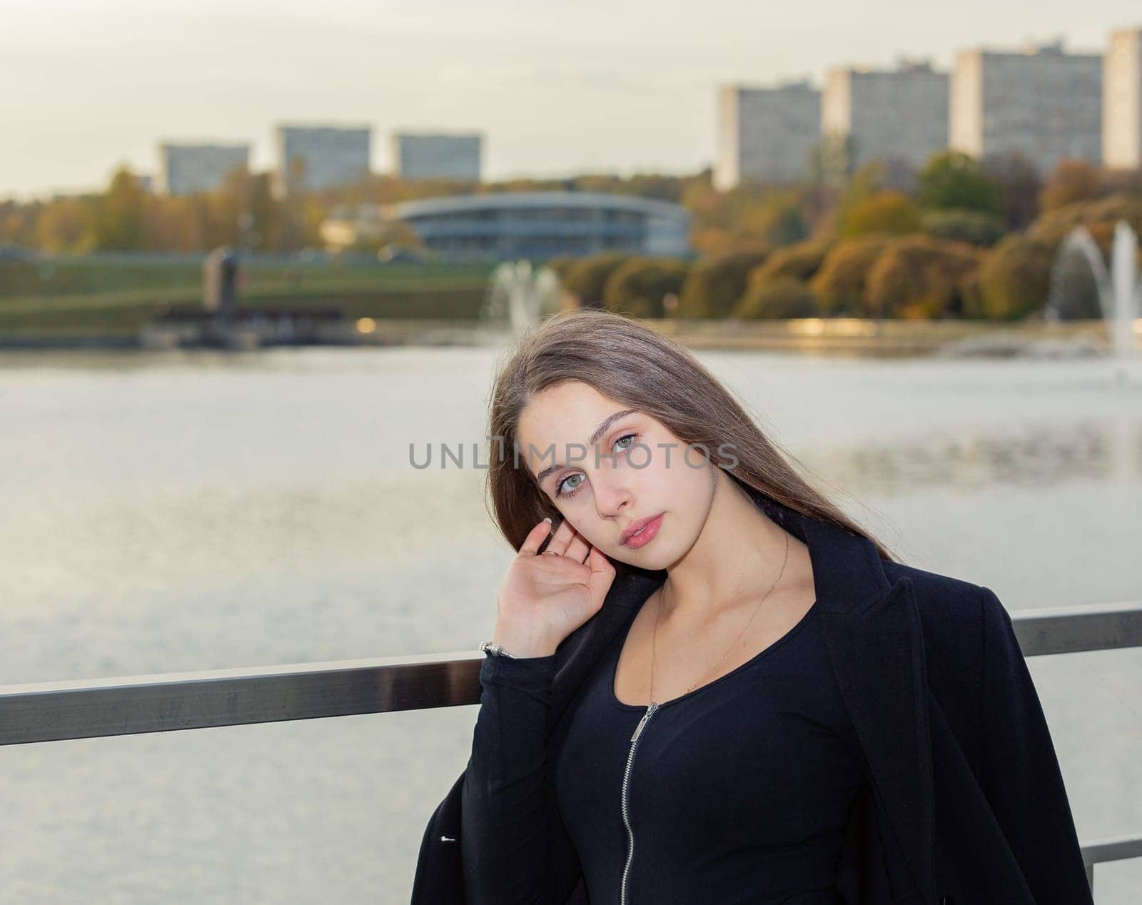 Portrait of a girl on a bridge near a pond in a city park