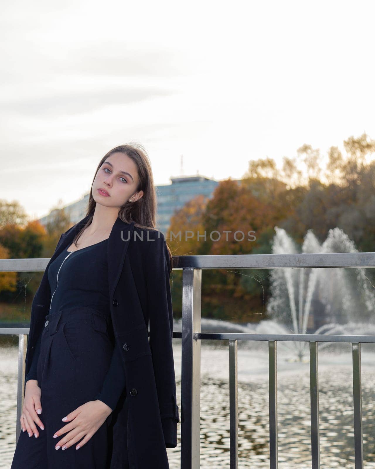 Portrait of a girl on a bridge near a pond in a city park