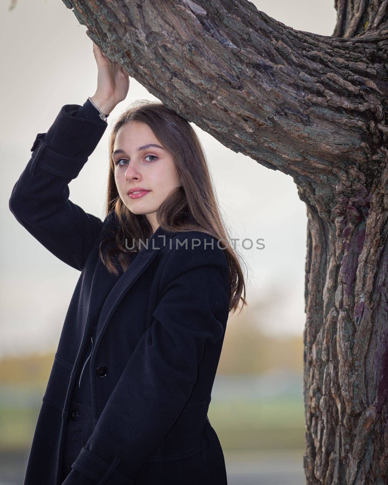 Portrait of a beautiful girl in the park near a tree