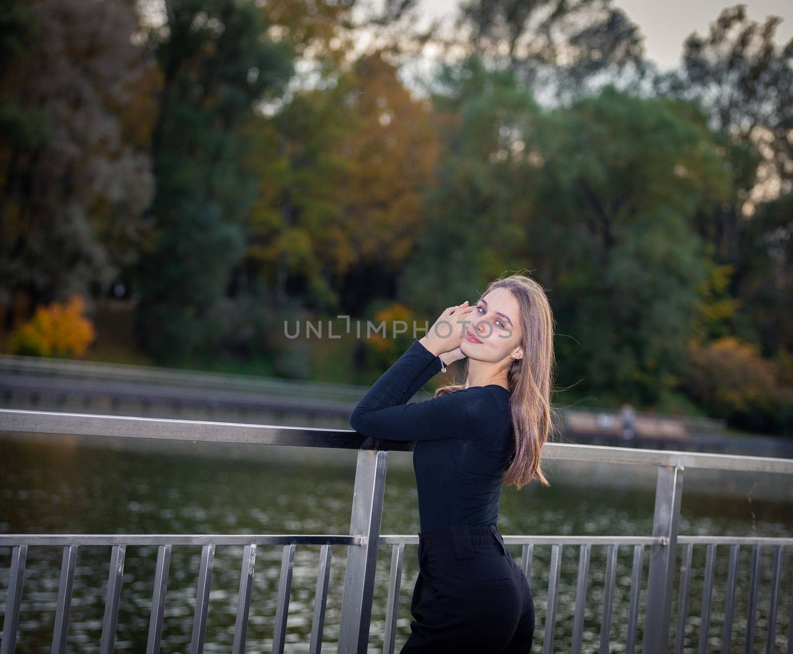 Portrait of a beautiful girl near a pond in a city park