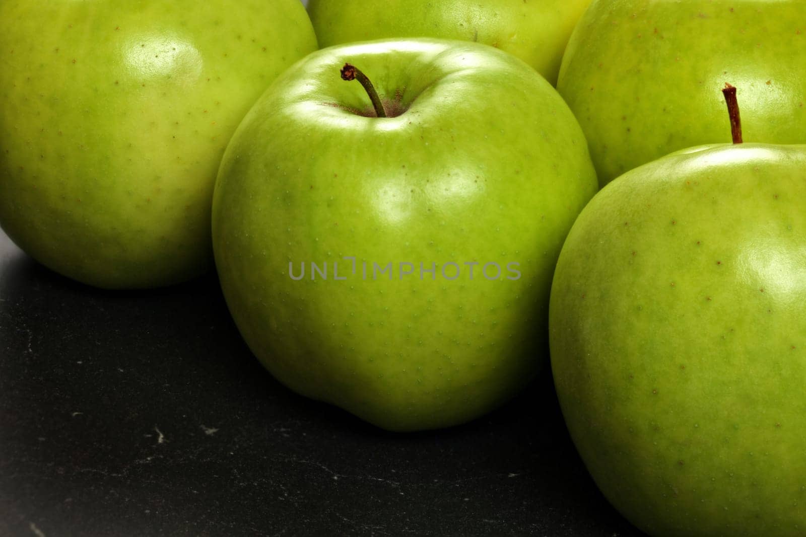 Closeup of green apples on black board by Ivanko