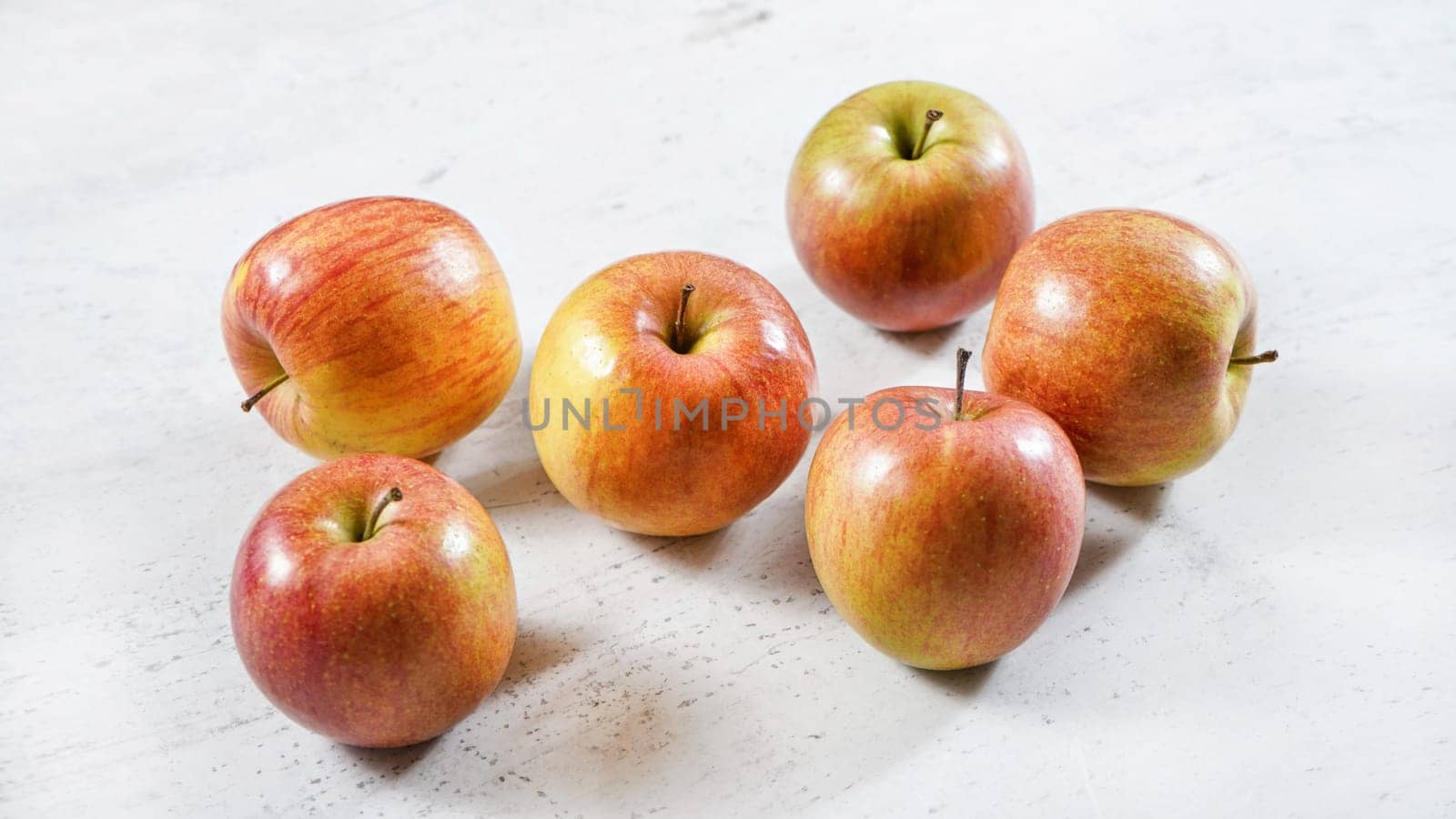 Red / yellow shiny apples (kiku variety) on white working board