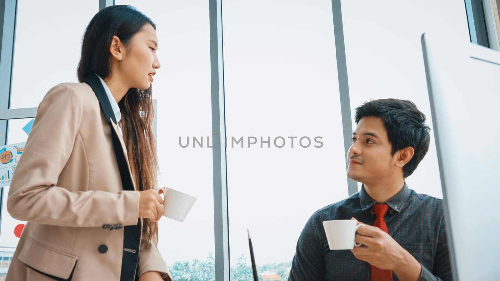 Two business people talk project strategy at office meeting room. Businessman discuss project planning with colleague at modern workplace while having conversation and advice on financial report. Jivy