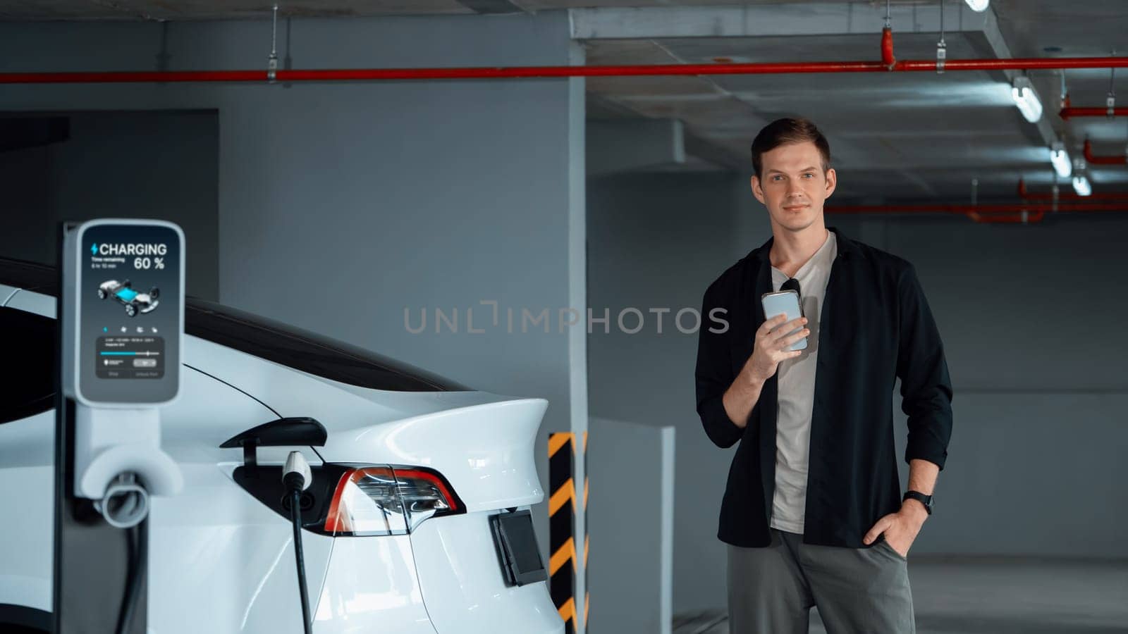 Young man travel with EV electric car to shopping center parking lot charging in downtown city showing urban sustainability lifestyle by green clean rechargeable energy of electric vehicle innards