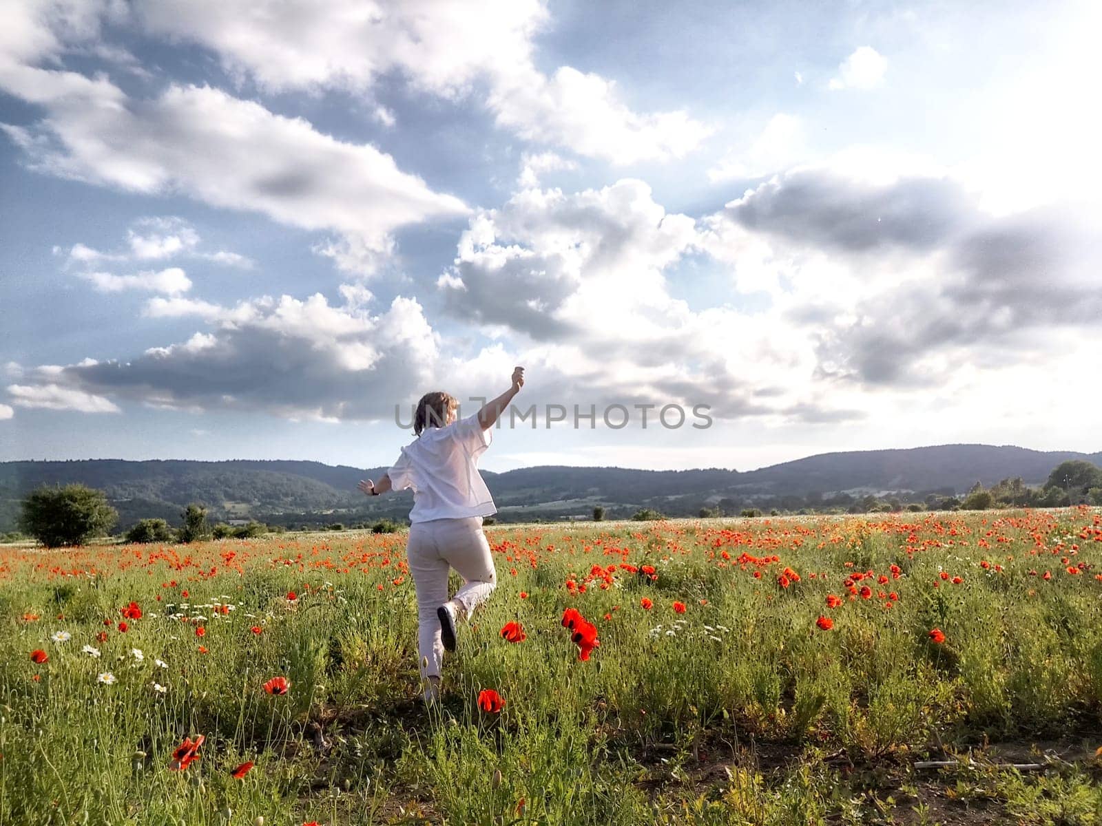 A happy girl in a poppy field. The journey of a middle-aged woman in summer. A tourist on trip