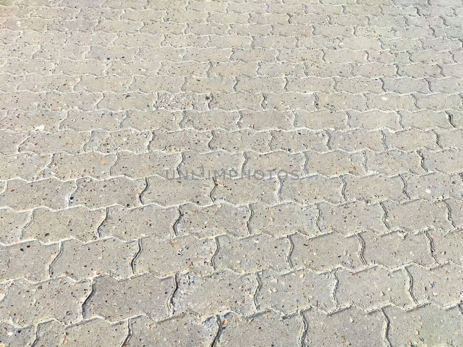 A close-up view of concrete pavement surface, showcasing interlocking pavers arranged in a diagonal pattern