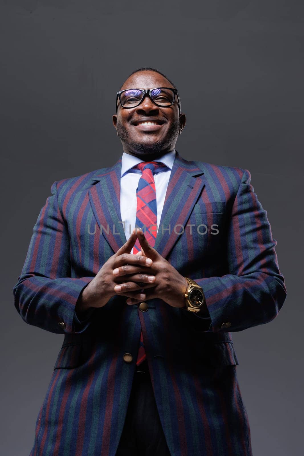 Handsome smiling african american businessman in suit and tie on clean grey background, shot from below, startup concept