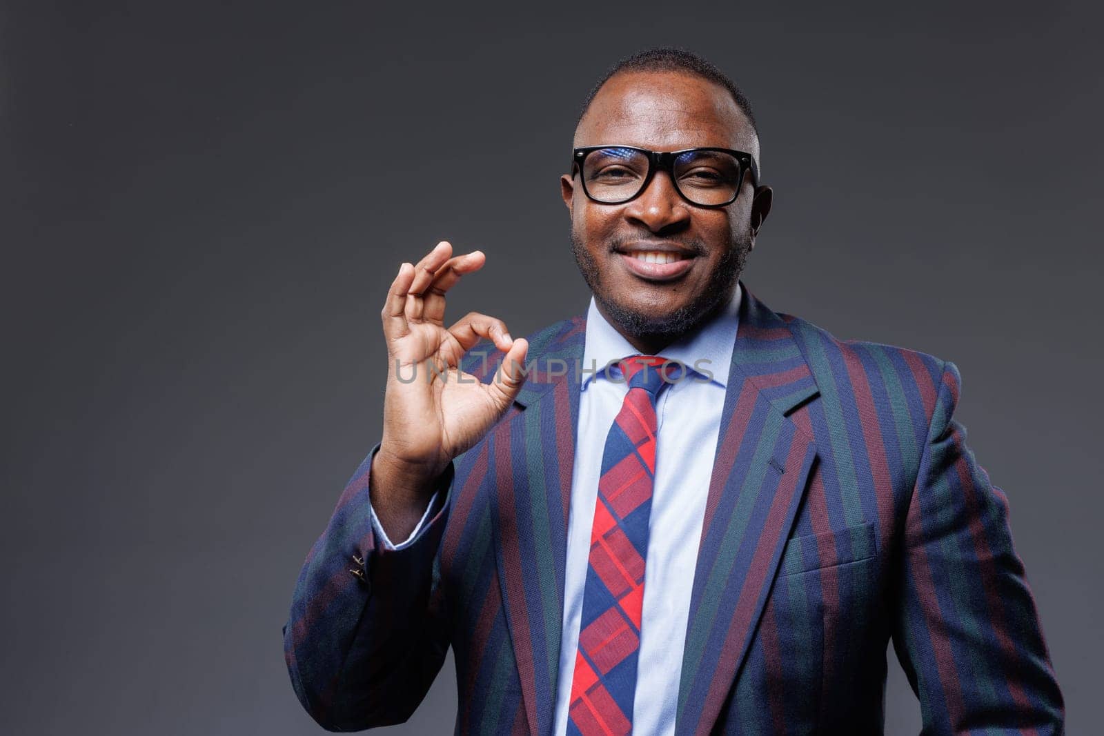 confident handsome african businessman showing ok sign, on gray background, concept of successful business