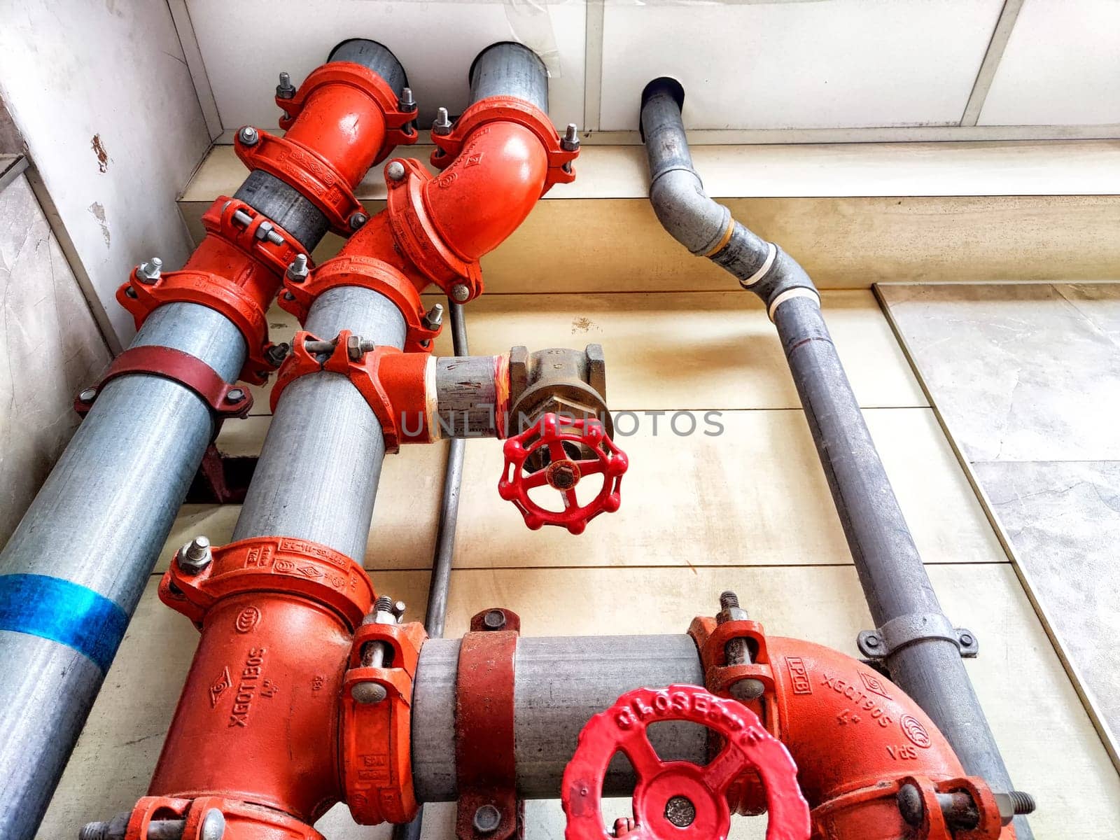 Kirov, Russia - April 09, 2024: A detailed view of a plumbing setup featuring multiple red valves and gray pipes affixed to the wall in a commercial interior.