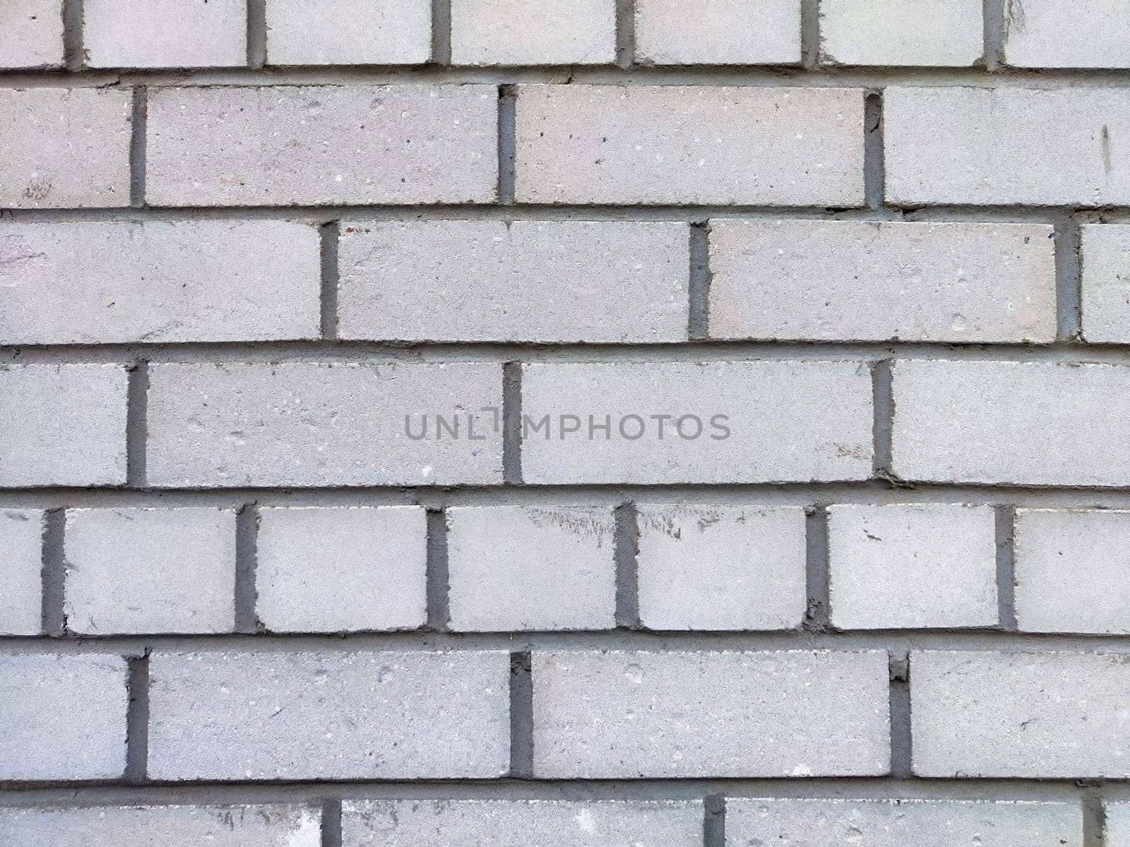 Smooth gray bricks are tightly arranged in a repetitive pattern on the wall.