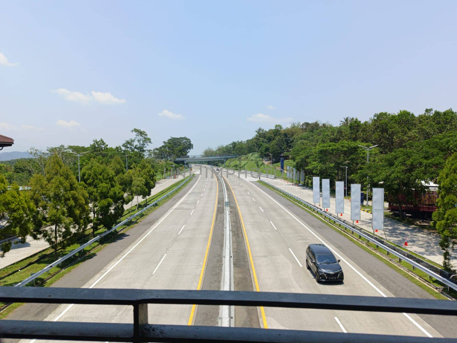 A highway with a bridge over it and cars driving on it. The cars are mostly white and black