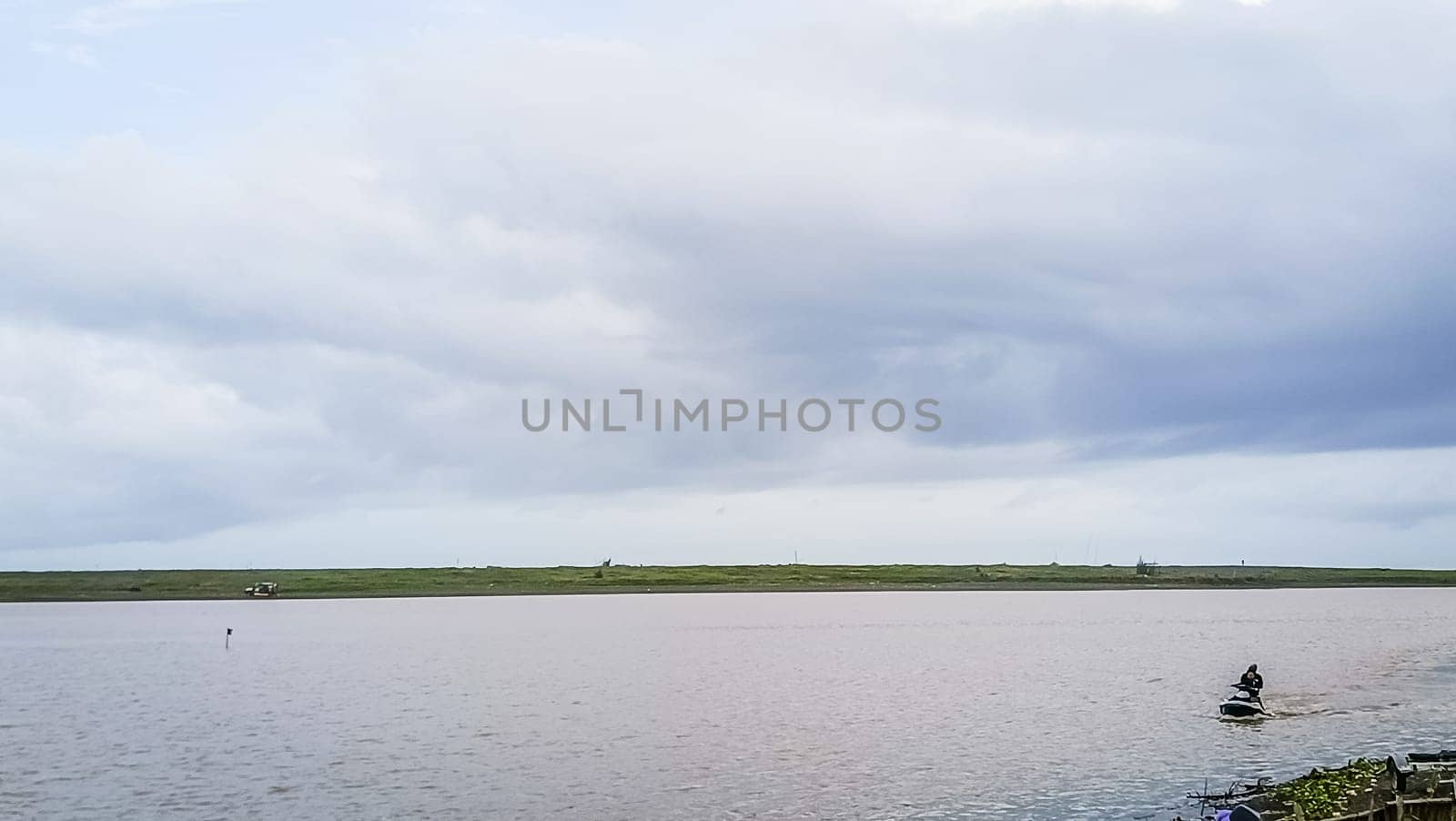 A beach with a calm water. The sky is cloudy and the water is calm