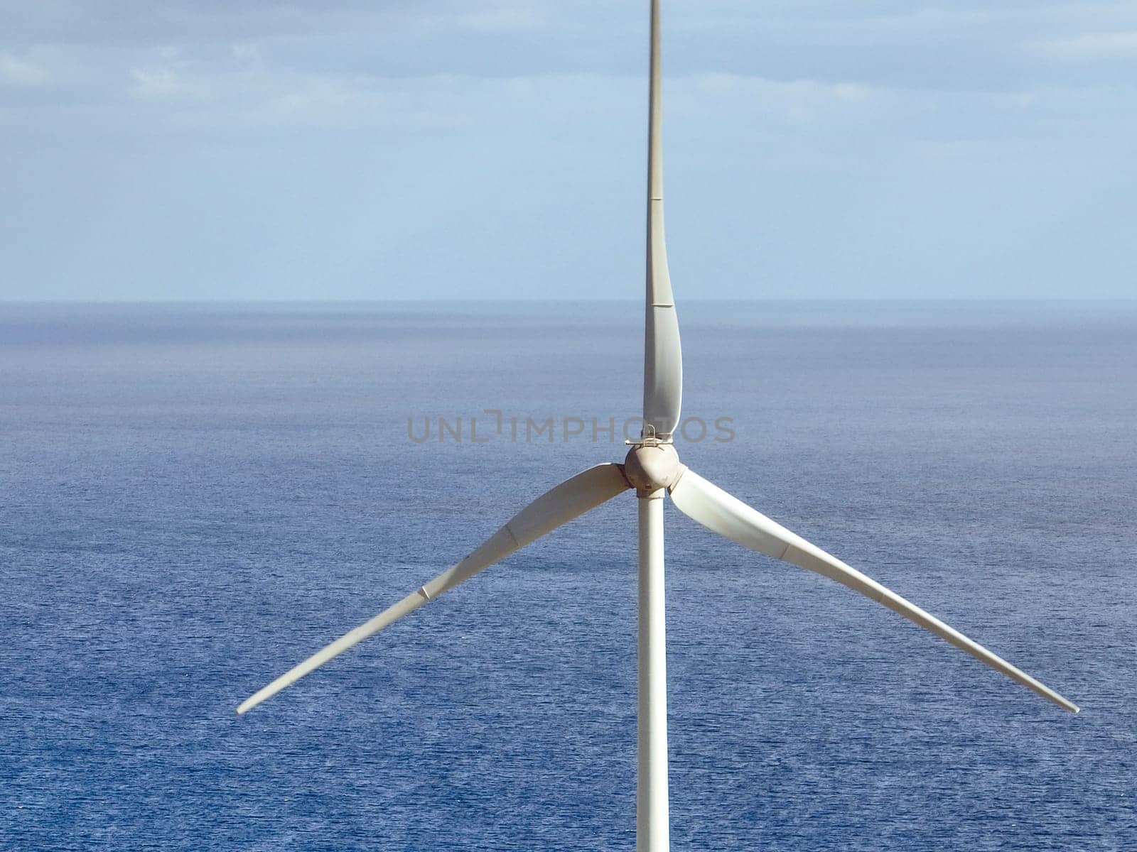 Wind power station with wind turbines, windmill propellers spinning in the wind, closeup view. Development of green ecological alternative energy on the islands of the Atlantic Ocean.