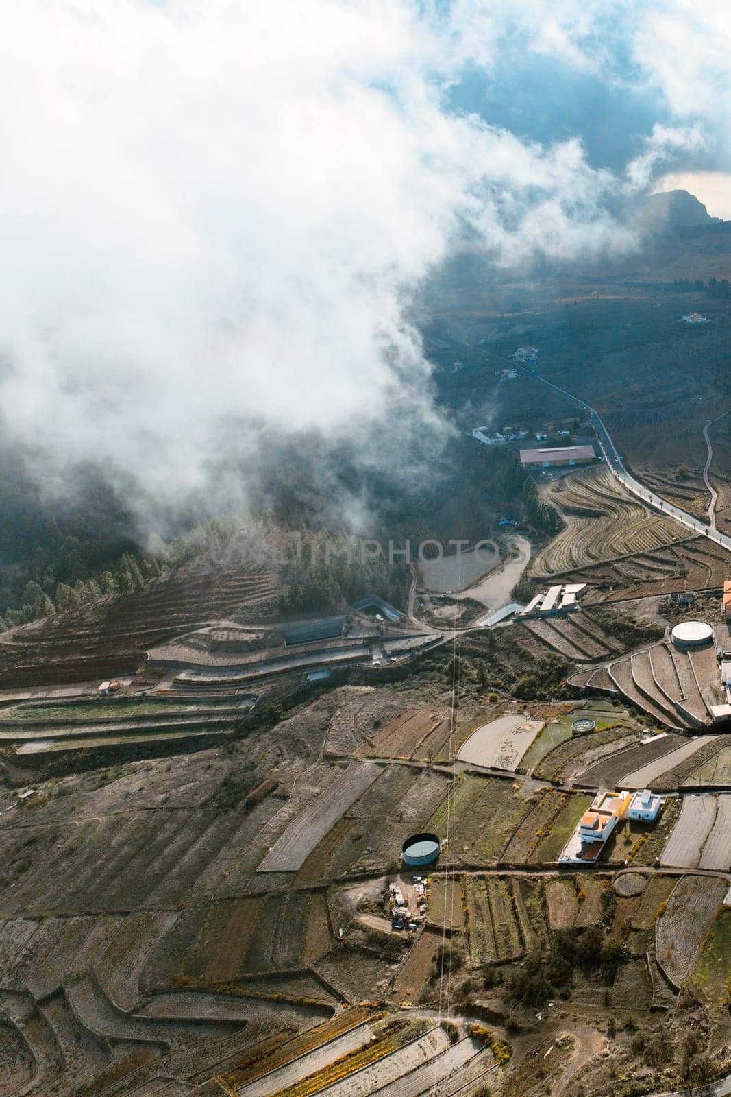 Dramatic view of a beautiful village and terraces with vineyards of Vilaflor, Tenerife Canary Islands, scenic view from above from a drone of a sunny picturesque valley and clouds.