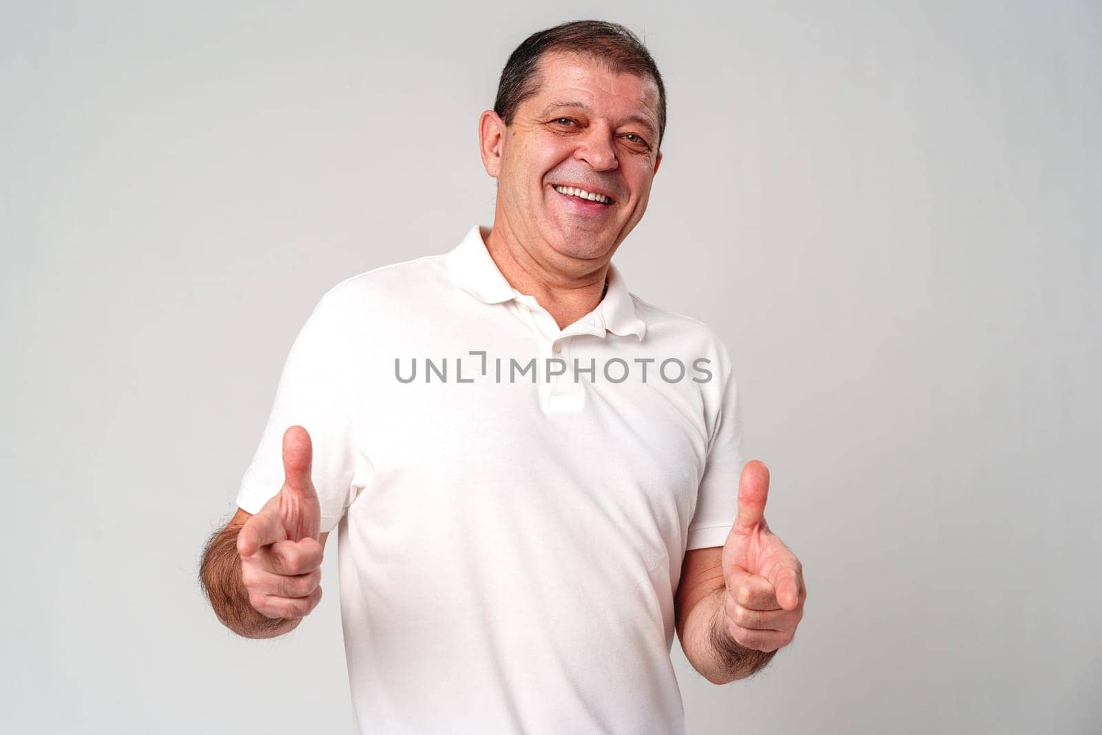 An older man smiling and reaching out with both hands in studio