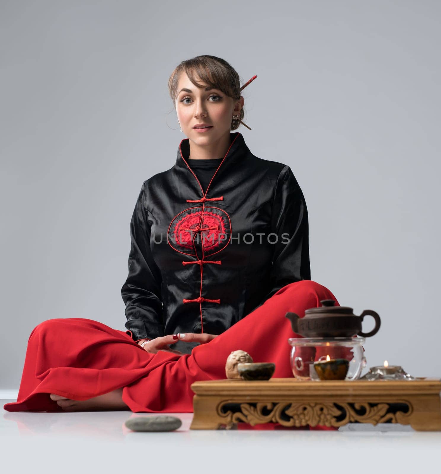 Woman practicing wushu sitting by table laid for chinese tea ceremony shot