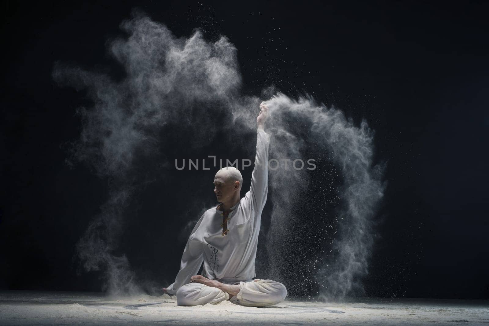 Man doing yoga in white dust cloud in dark room full-length shot - concept of energy