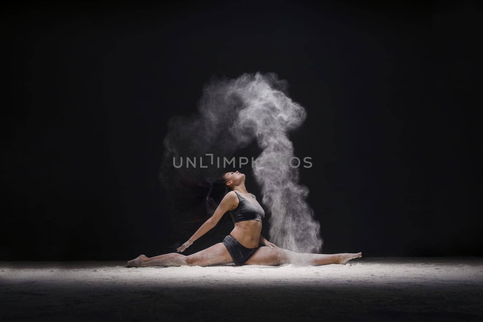 Female sitting in a split in a white dust cloud profile view