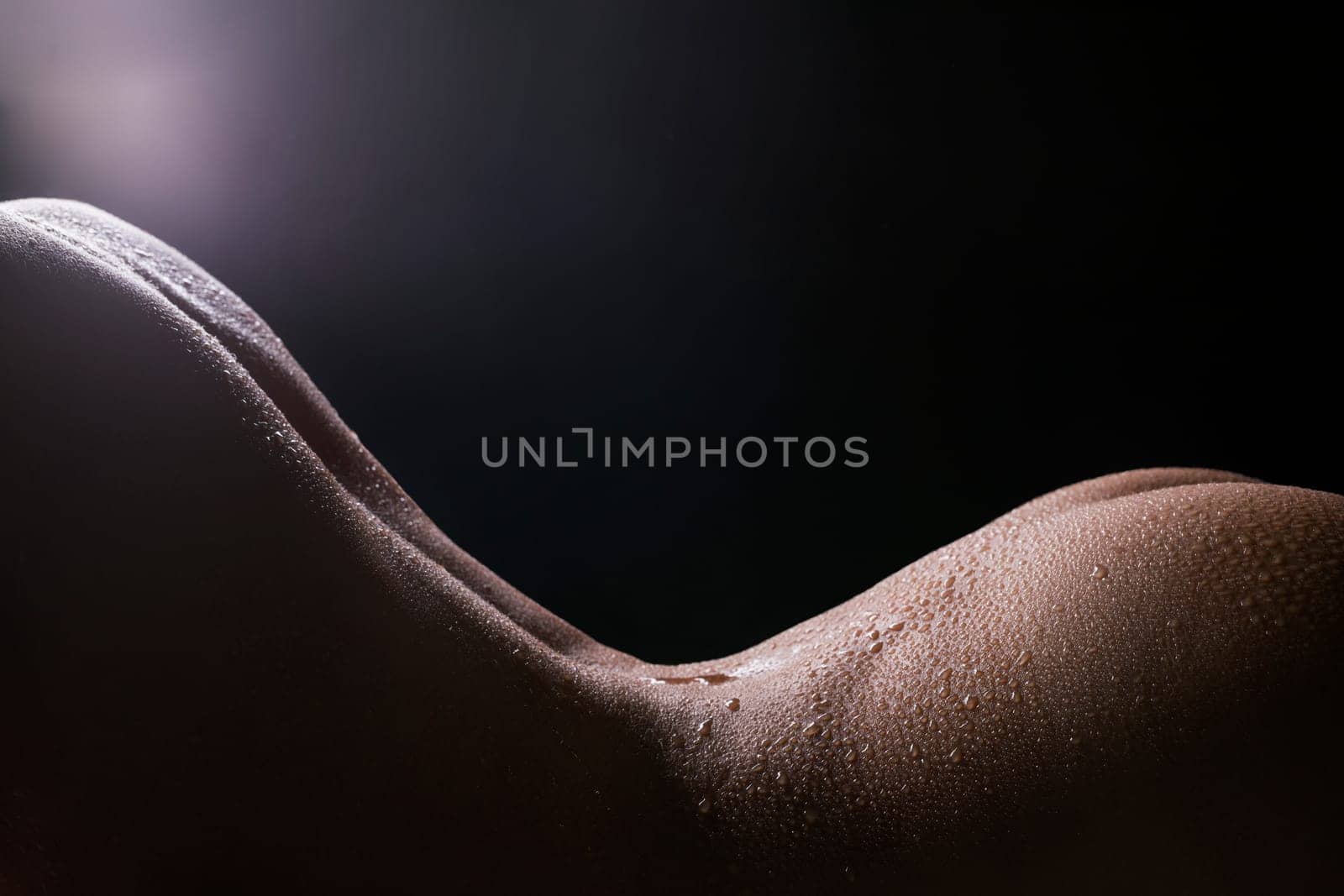 Water drops on nude woman body cropped view on black background