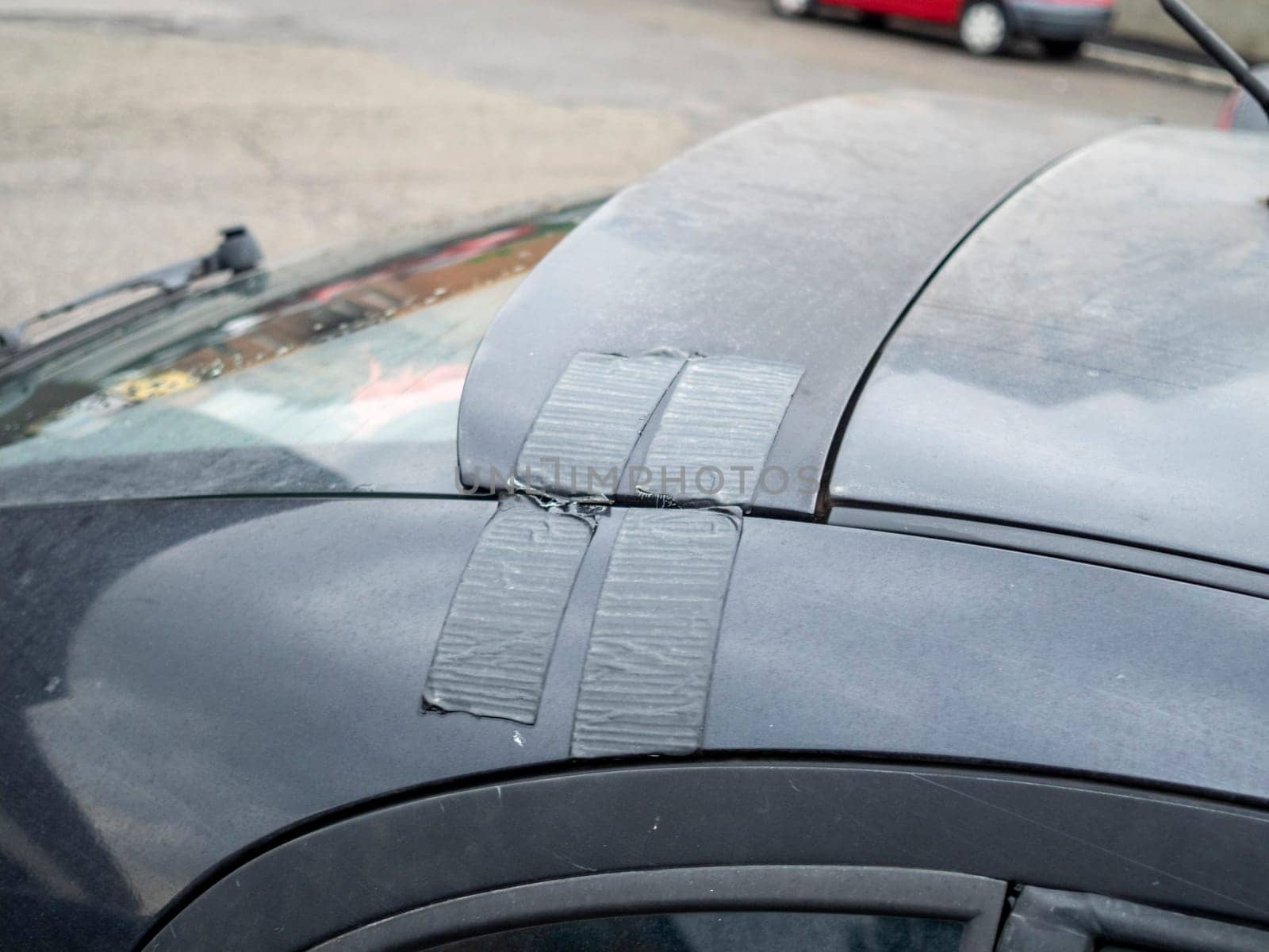 Cremona, Lombardy, Italy October 15th 2024 Close up of a broken car spoiler repaired with duct tape, showing a temporary and makeshift fix