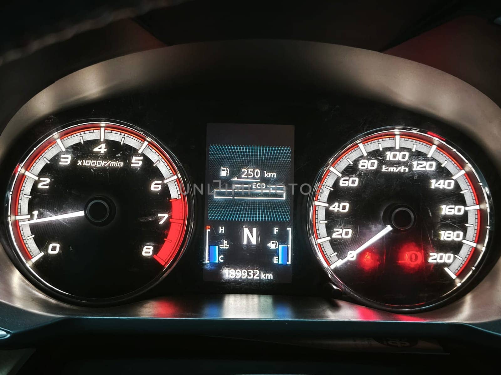 A car dashboard with a digital display, ECO mode indicator, and a tachometer indicator.