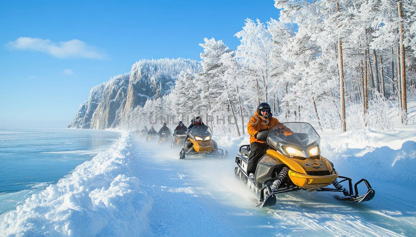 Snowmobilers enjoying a scenic ride on a frozen lake surrounded by snowy mountains