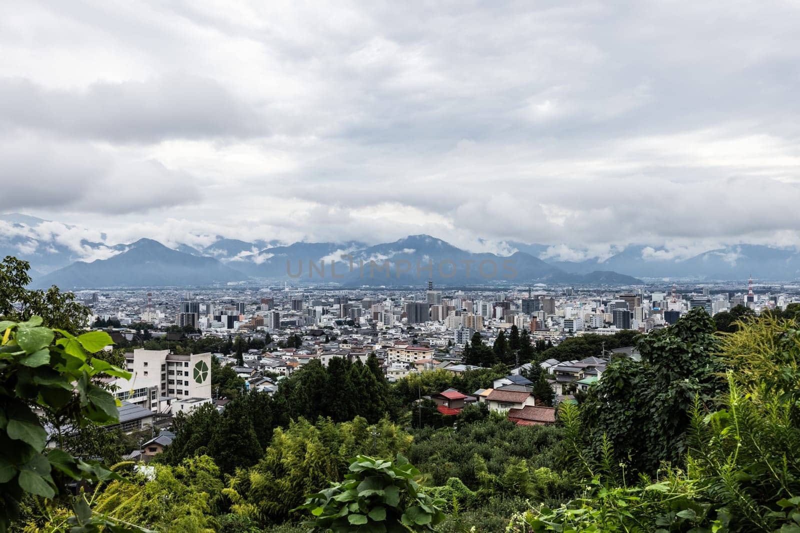 NAGANO, JAPAN - SEPTEMBER 19, 2024: An aerial view over the beautiful town of Nagano in Nagano Prefecture. Surrounded by mountains on a stormy warm autumn morning.