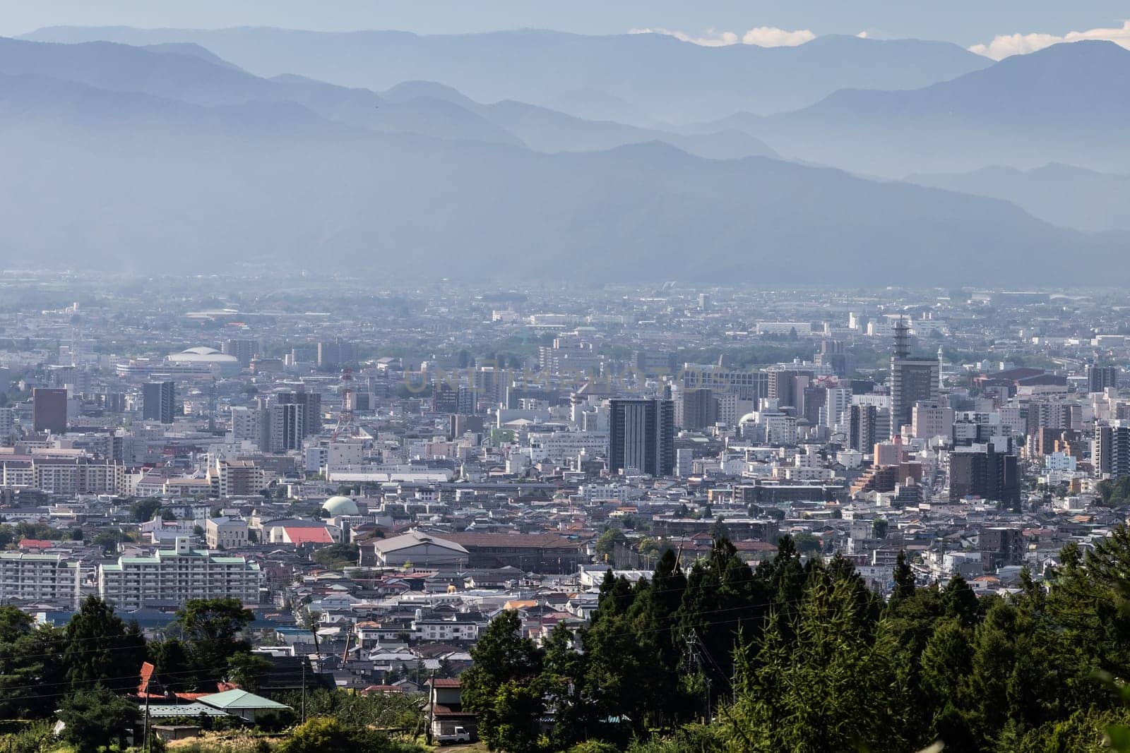 NAGANO, JAPAN - SEPTEMBER 20, 2024: An aerial view over the beautiful town of Nagano in Nagano Prefecture. Surrounded by mountains on a clear warm autumn morning.