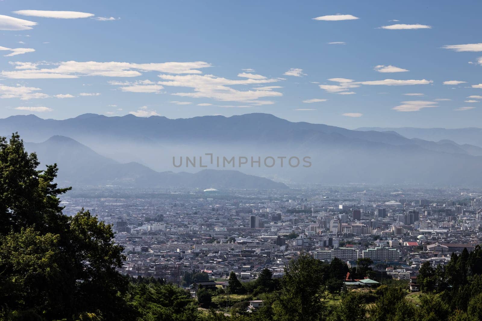 NAGANO, JAPAN - SEPTEMBER 20, 2024: An aerial view over the beautiful town of Nagano in Nagano Prefecture. Surrounded by mountains on a clear warm autumn morning.