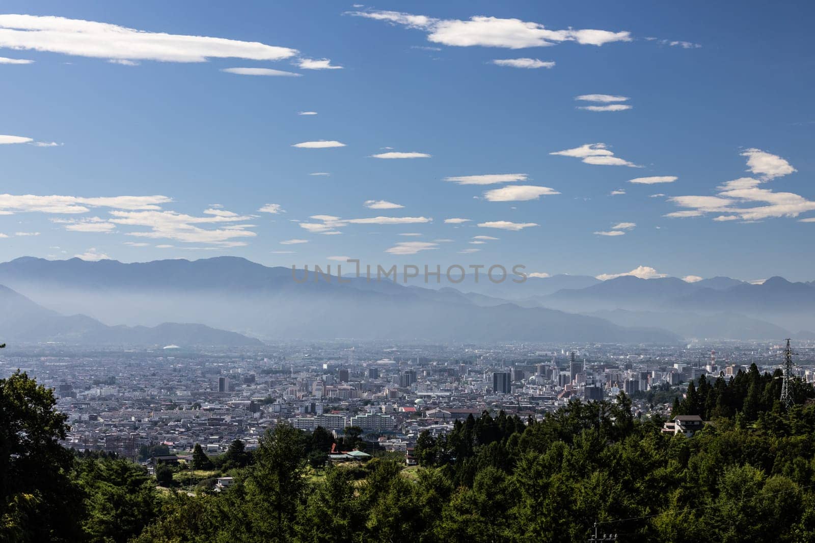 NAGANO, JAPAN - SEPTEMBER 20, 2024: An aerial view over the beautiful town of Nagano in Nagano Prefecture. Surrounded by mountains on a clear warm autumn morning.