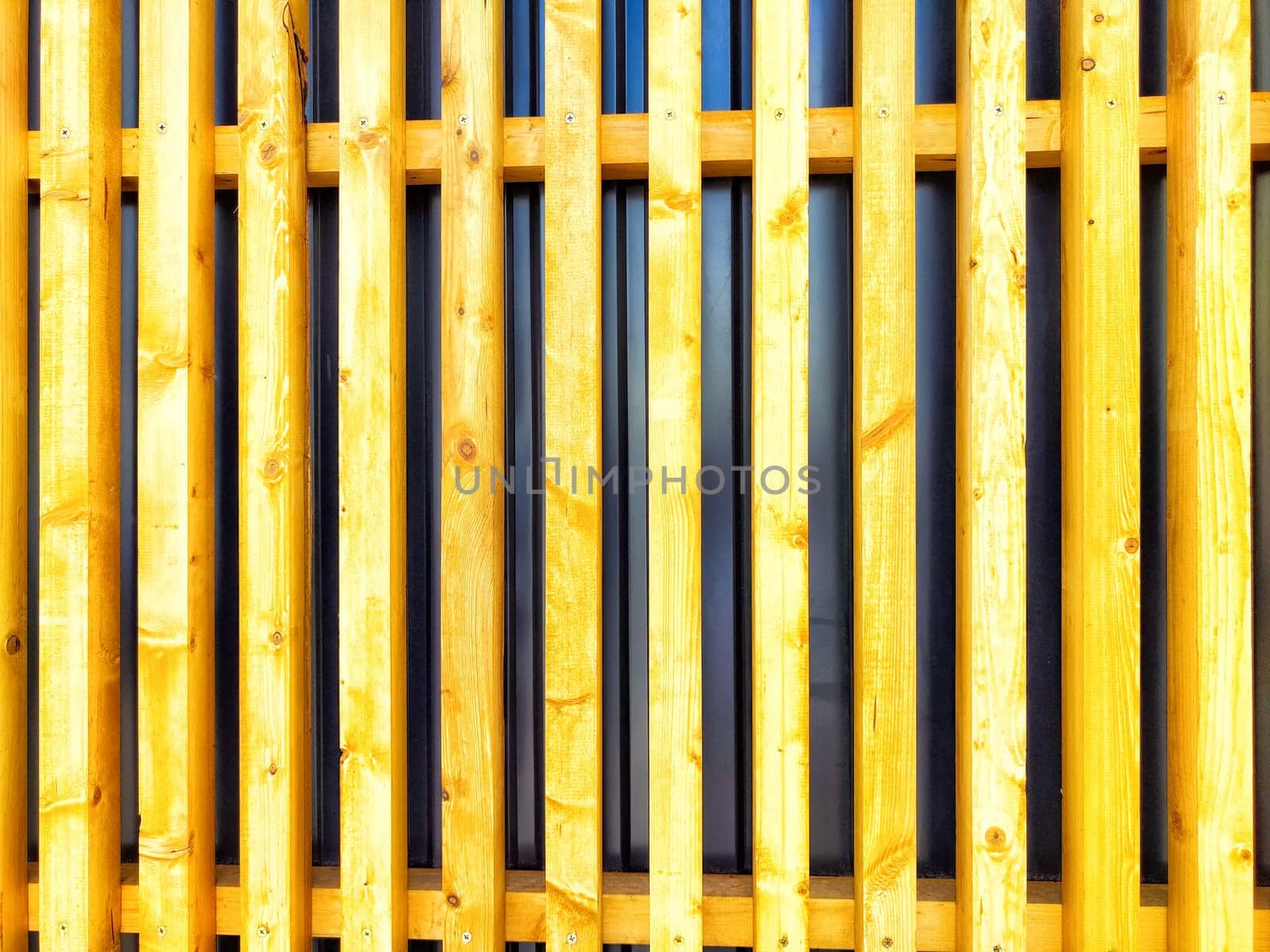 Wooden slats cover glass, forming an intriguing texture against a bright surface.
