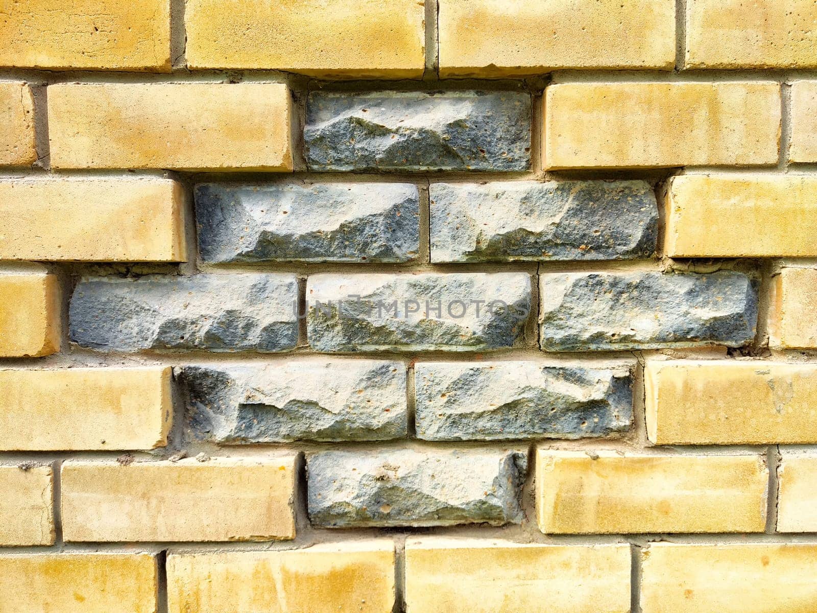 A captivating brick wall showcases a unique combination of smooth yellow bricks and rough gray stones, offering a perfect area for text or designs.
