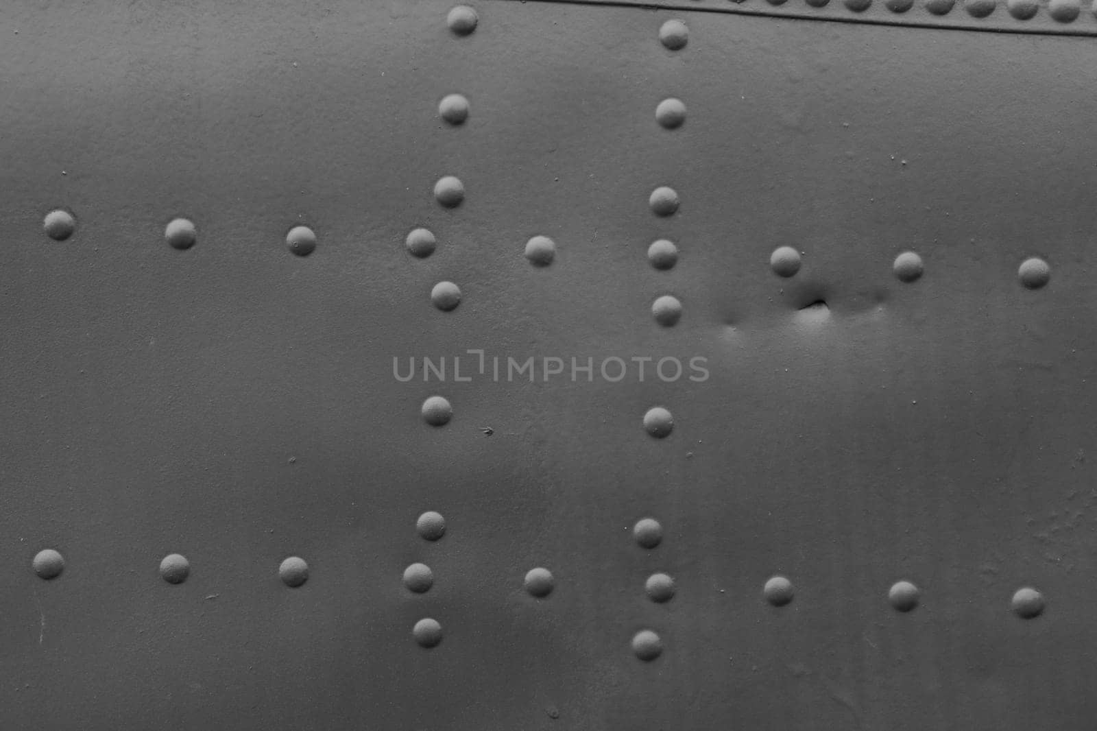 The fuselage skin of an old military aircraft with rivets. Close-Up of Gray Metal. Metal abstract background.
