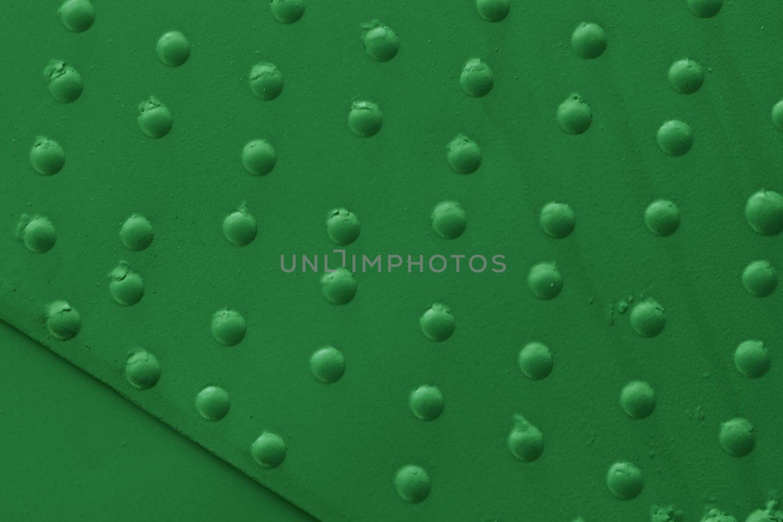Metal plating with close-up rivets. Military armor of old equipment painted with green paint.