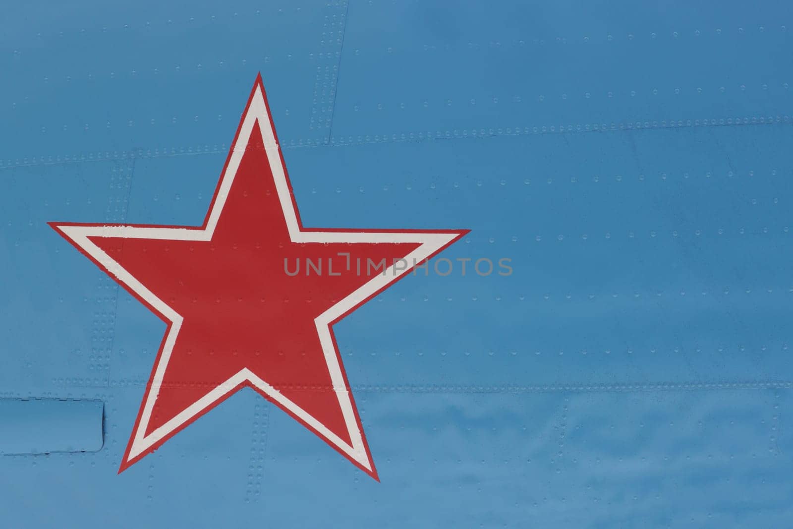 An army star with a white border on a green background of metal plating with rivets.