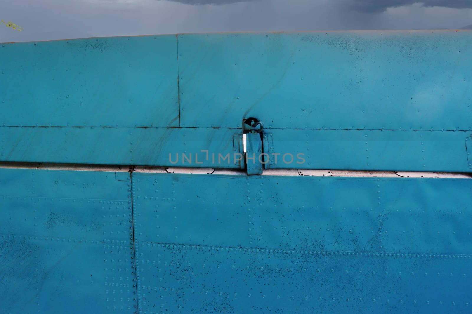 Part of an airplane wing painted blue, viewed from below.