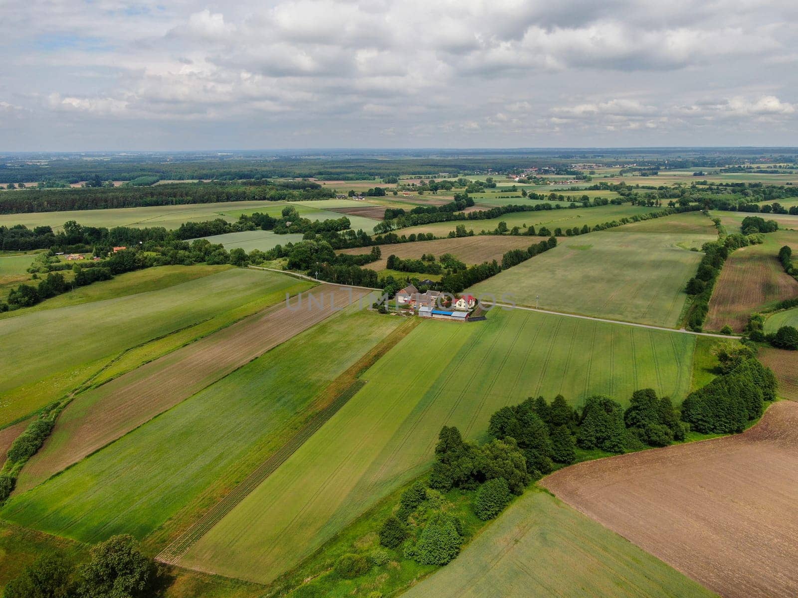 Aerial view of the dark, atmospheric sky over a small Polish village among green fields. High quality photo