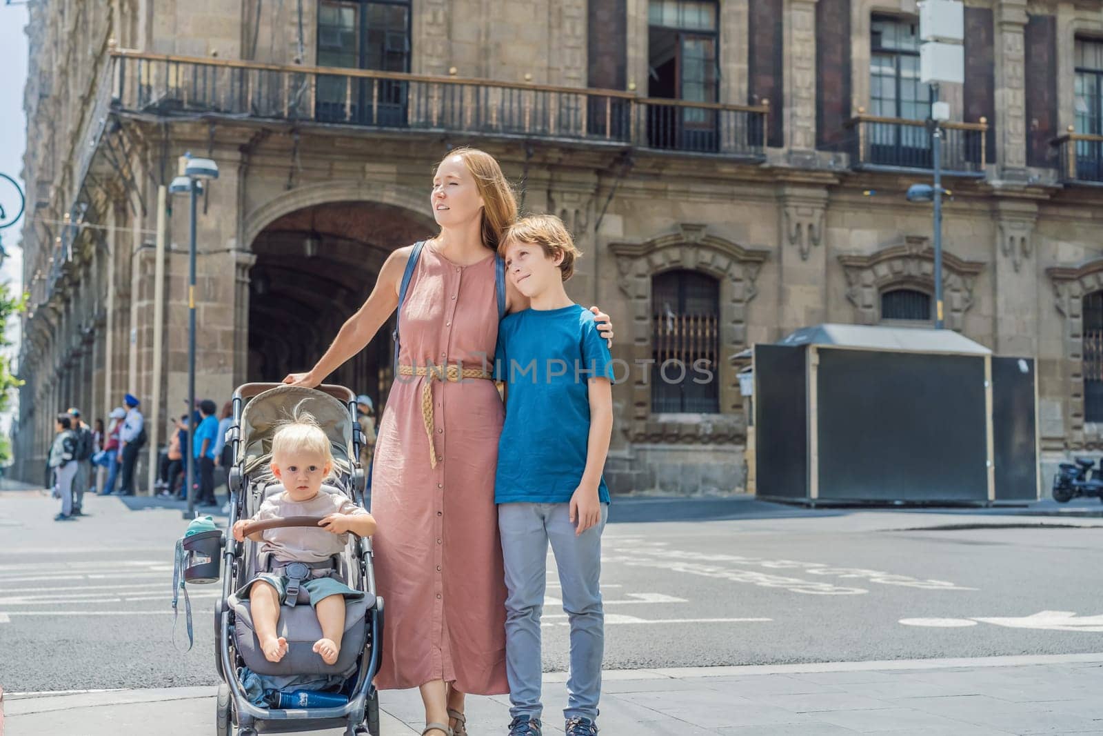 Mother, baby son and teenage son tourists in the central square of Mexico City, Zocalo. Family travel, cultural exploration, and historic architecture concept.