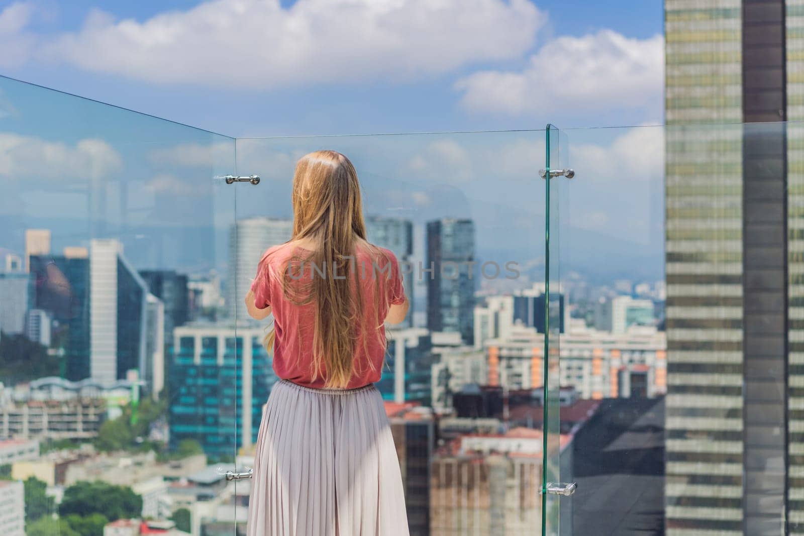 Female tourist or businesswoman standing on a skyscraper rooftop with a panoramic view of Mexico City. Travel or international business in Mexico concept.