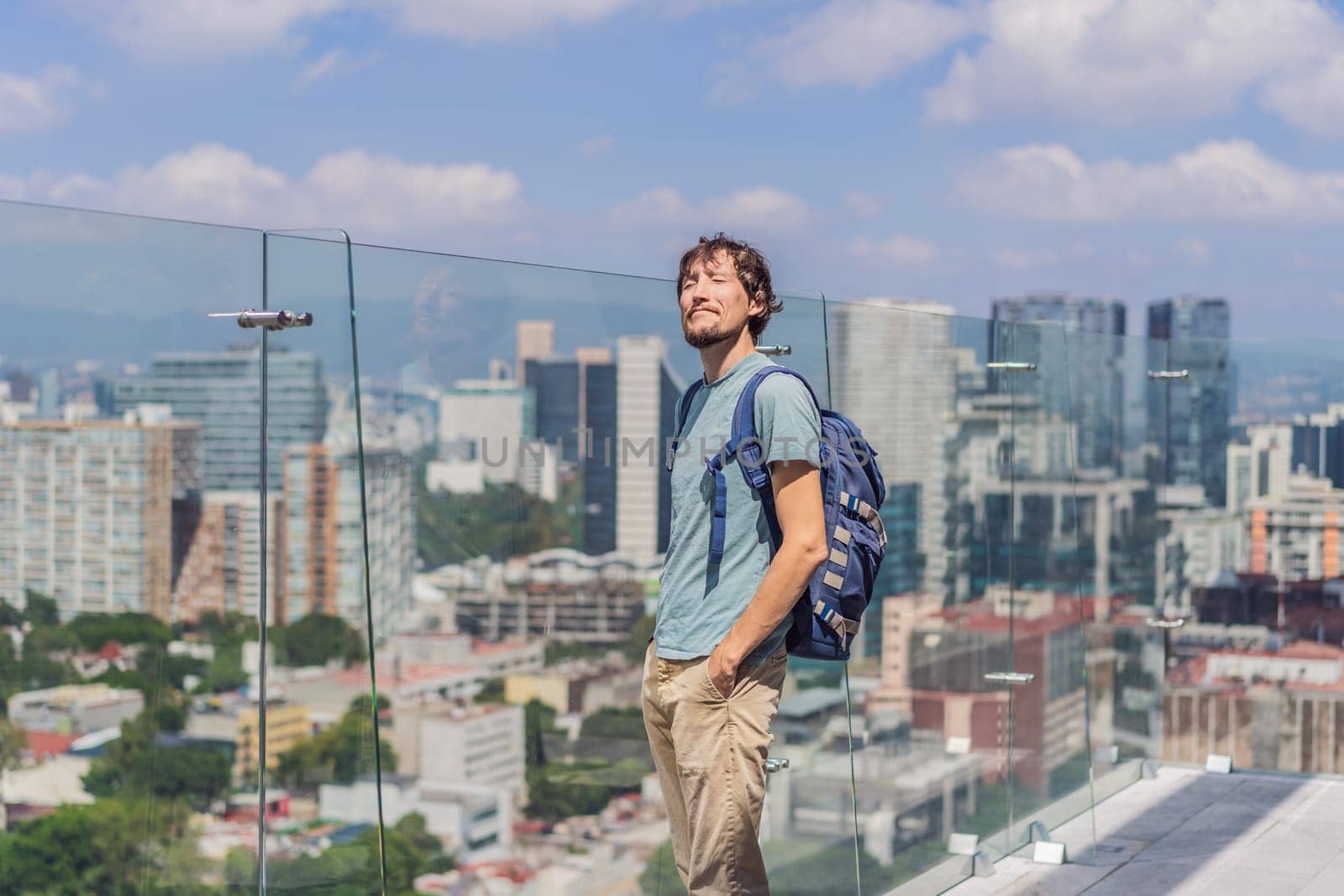 Male tourist or businessman standing on a skyscraper rooftop with a panoramic view of Mexico City. Travel or international business in Mexico concept.