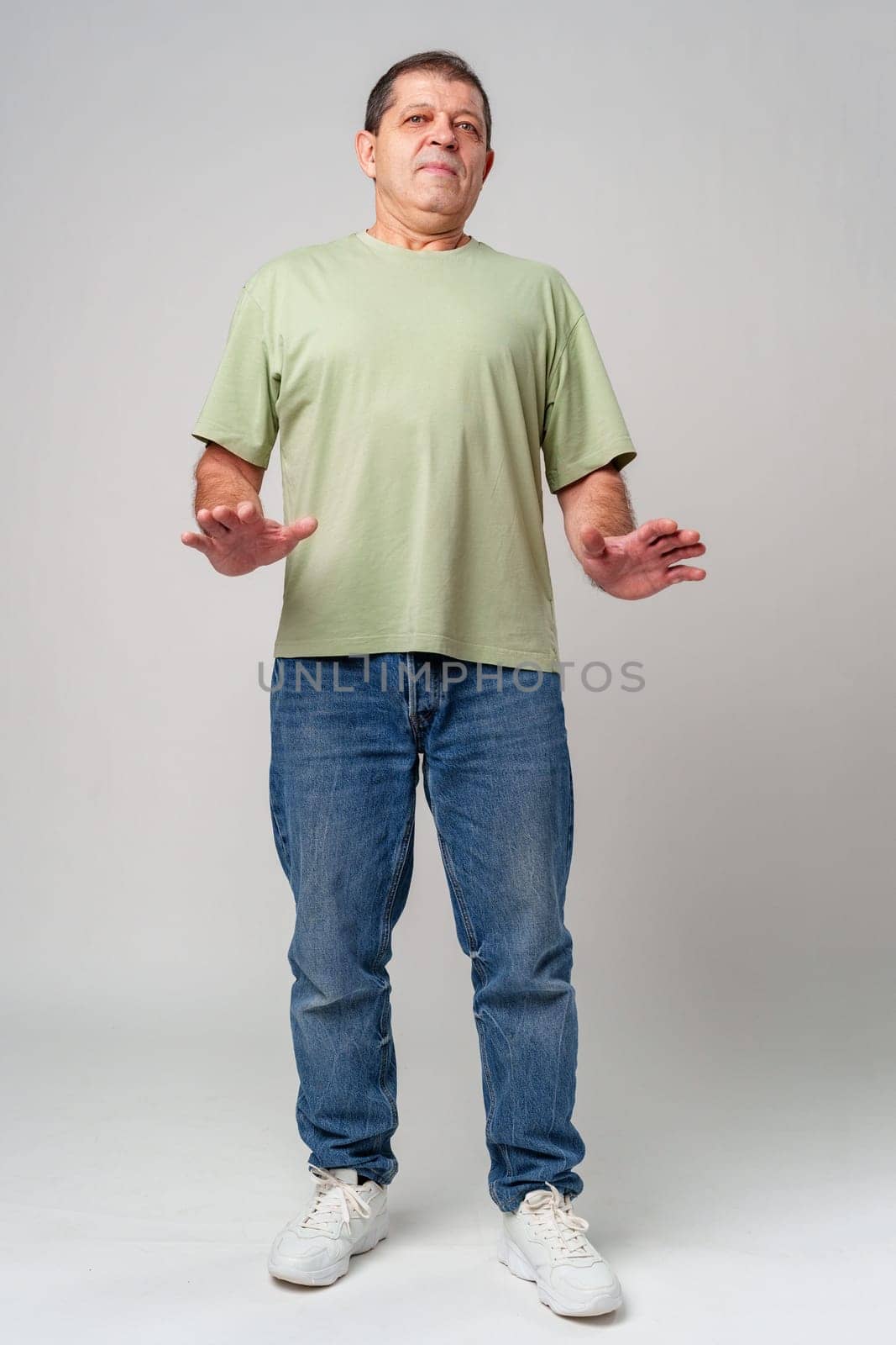 An older man standing confidently in casual attire, wearing a green shirt close up