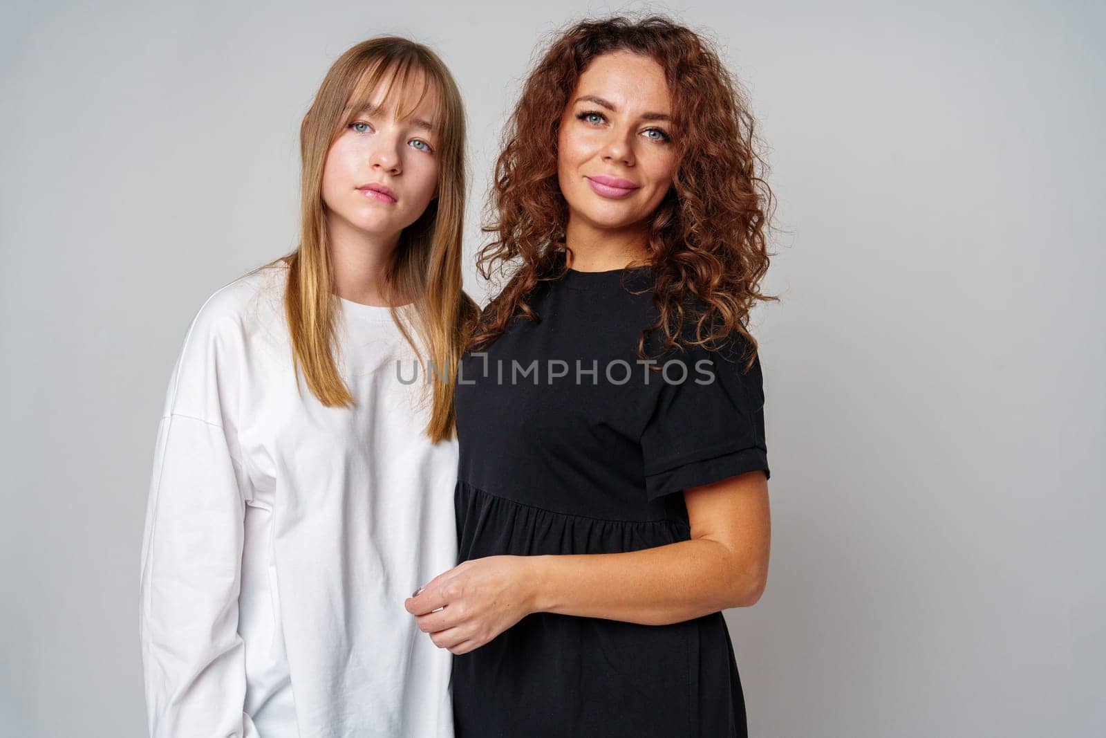 Two women standing together, one in white and the other in black, showcasing a warm connection in studio