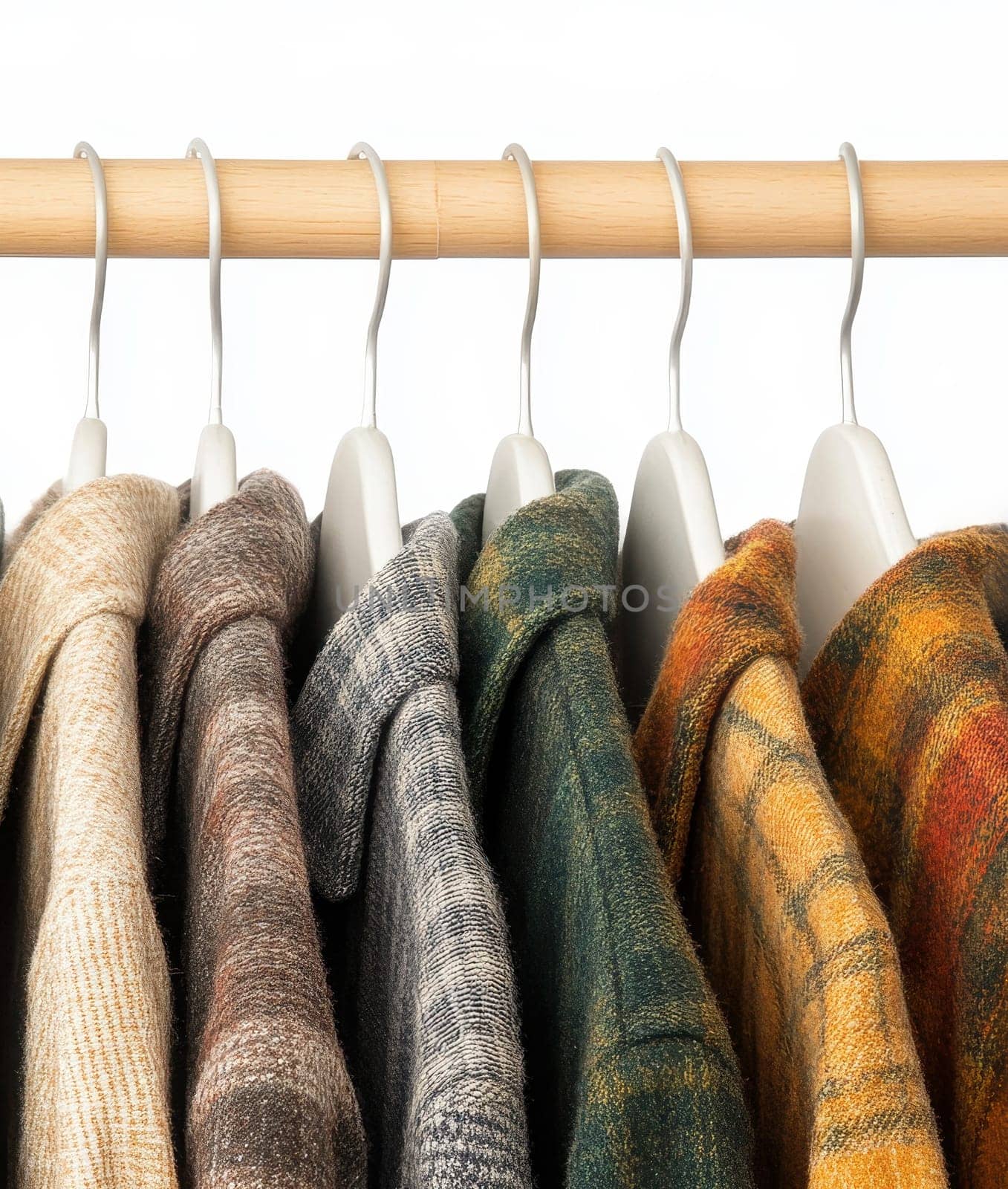 Collection of plaid flannel shirts in various colors hanging on wooden rack, autumn and winter casual fashion wardrobe essentials. High quality illustration