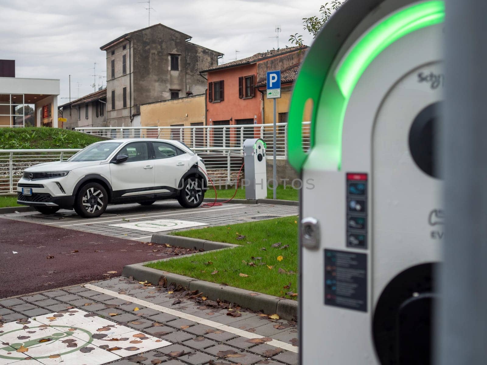Cremona, Lombardy, Italy October 15th 2024 White electric car charging at a public charging station, promoting sustainable transportation and eco friendly practices in an urban environment
