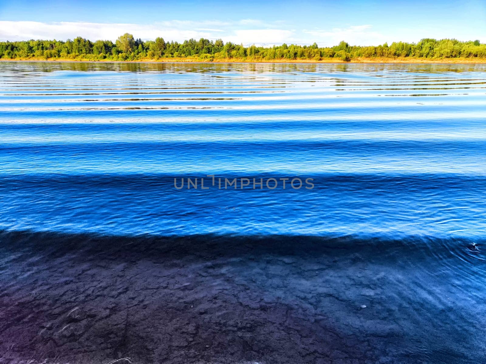 Calm water reflects the blue sky while gentle ripples create patterns along the surface.