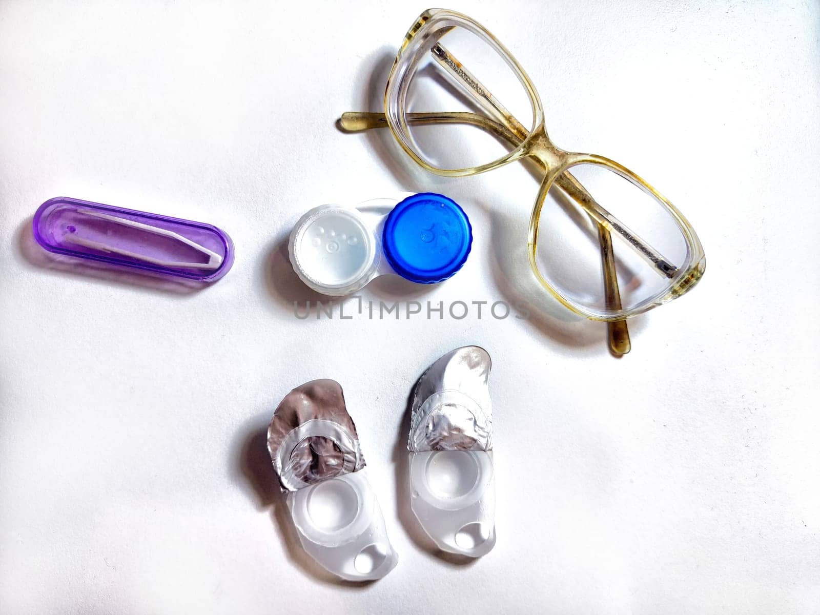 A pair of stylish glasses is placed alongside contact lens case and solution, showcasing daily eyewear essentials for eye care